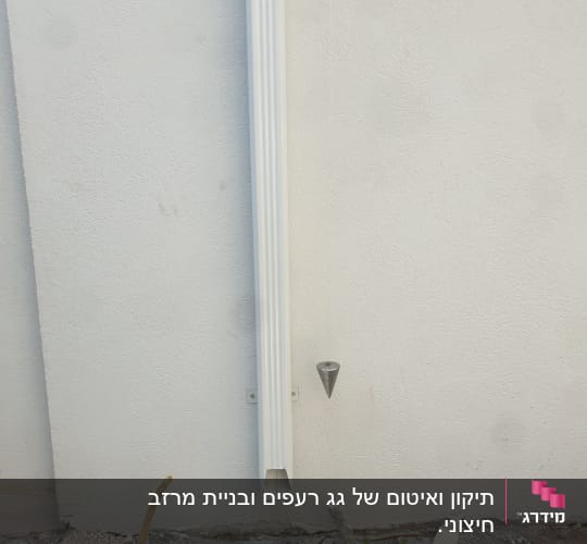 צינור מרזב לבן מחובר לקיר חיצוני